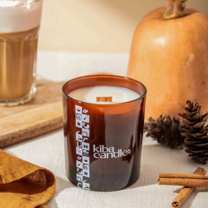 Coconut wax candle from Kiba collection displayed with decorative elements like cinnamon sticks and pine cones, evoking a cozy autumn atmosphere.